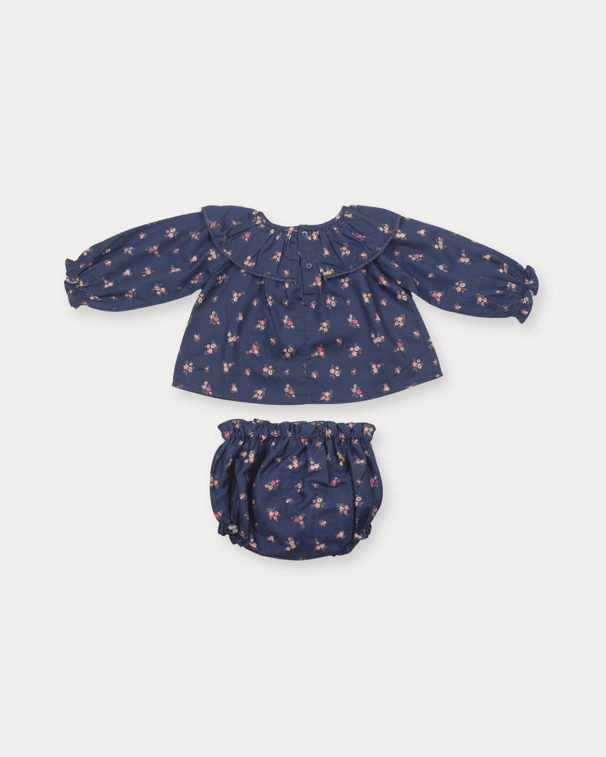 Early Sunday, Daisy Baby Blouse & Bloomer Set in Ditsy Bouquet Navy, made from Printed Cotton Satin fabric, featuring a frilly neckline with detailed lace yoke & gathered sleeves, shown in a back flat-lay view