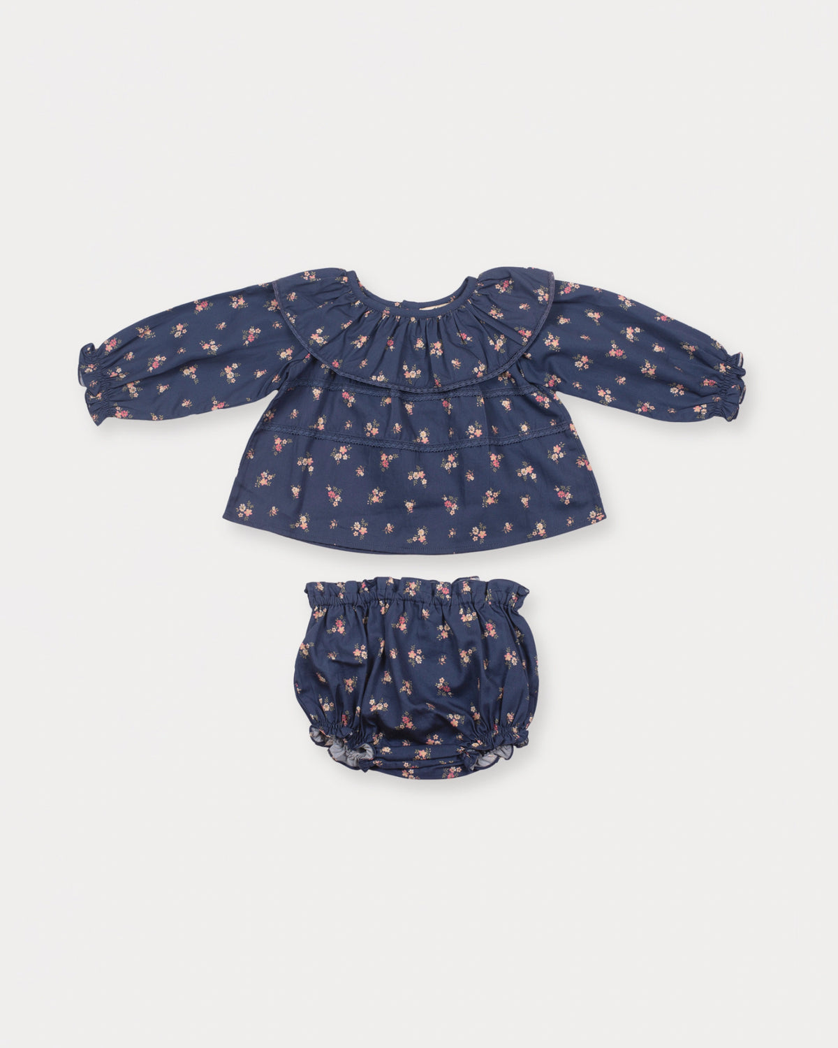 Early Sunday, Daisy Baby Blouse & Bloomer Set in Ditsy Bouquet Navy, made from Printed Cotton Satin fabric, featuring a frilly neckline with detailed lace yoke & gathered sleeves, shown in a front flat-lay view