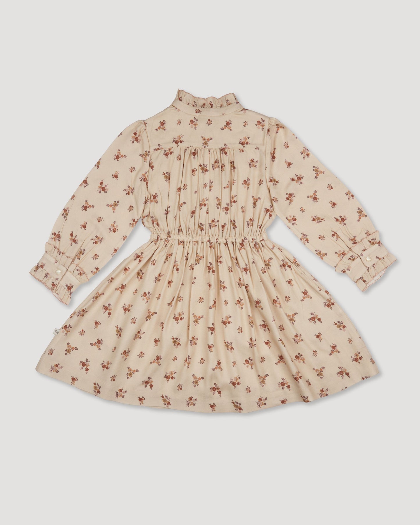 Early Sunday, Dawn Dress in Ditsy Bouquet Cream print, made from Printed Viscose Rayon Twill fabric, featuring Collar and sleeve cuffs trimmed with subtle ruffles for a nostalgic silhouette, shown in a back flat-lay view