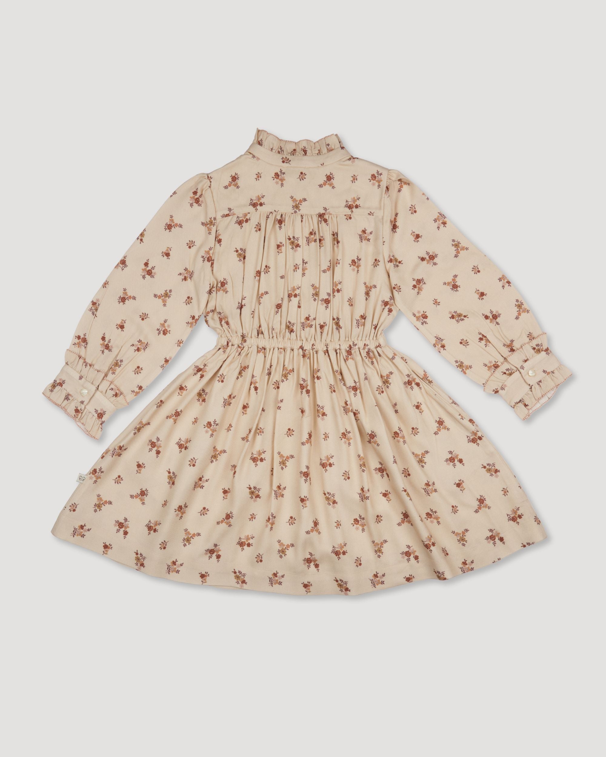 Early Sunday, Dawn Dress in Ditsy Bouquet Cream print, made from Printed Viscose Rayon Twill fabric, featuring Collar and sleeve cuffs trimmed with subtle ruffles for a nostalgic silhouette, shown in a back flat-lay view