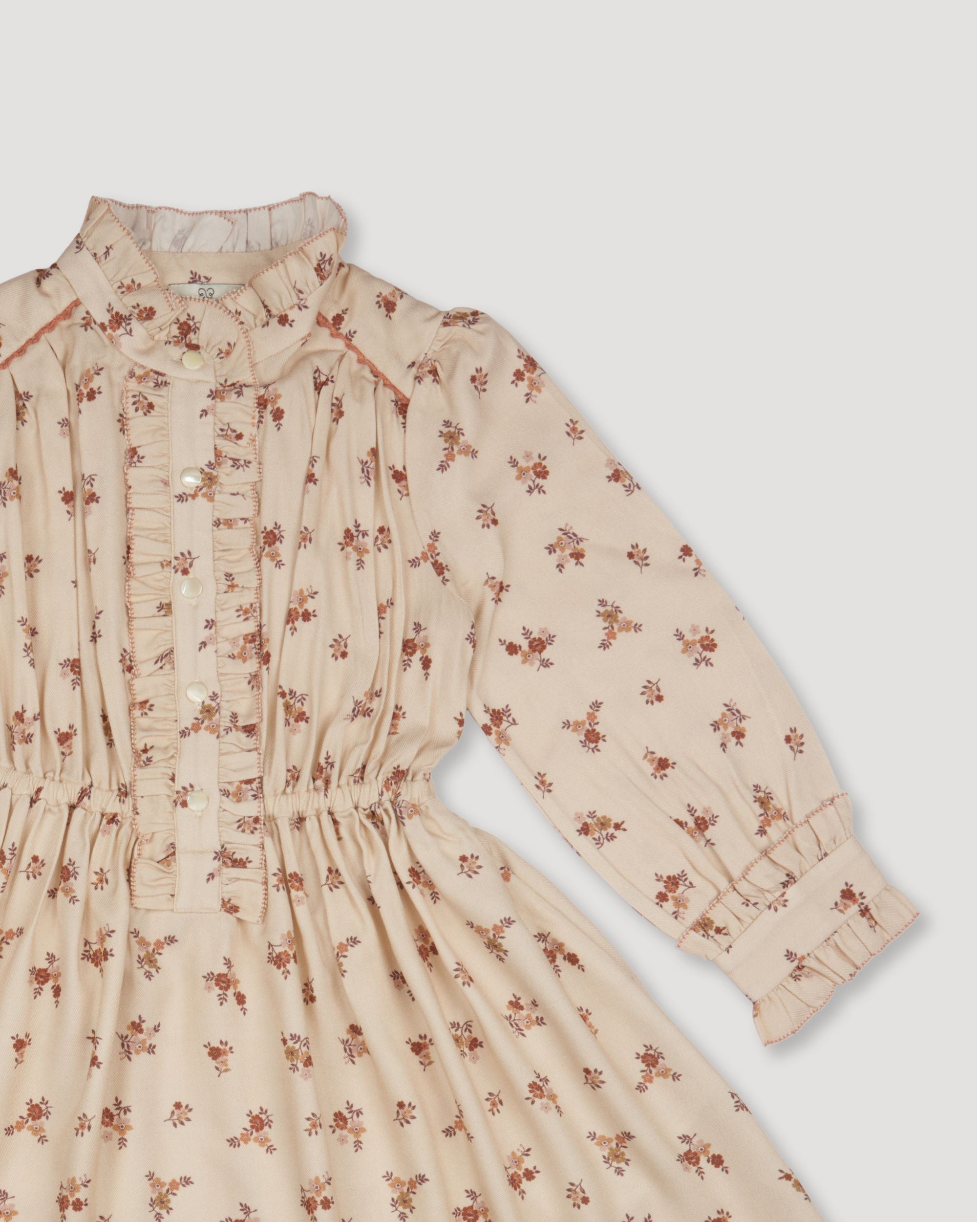 Early Sunday, Dawn Dress in Ditsy Bouquet Cream print, made from Printed Viscose Rayon Twill fabric, featuring Collar and sleeve cuffs trimmed with subtle ruffles for a nostalgic silhouette, shown in a closeup flat-lay view