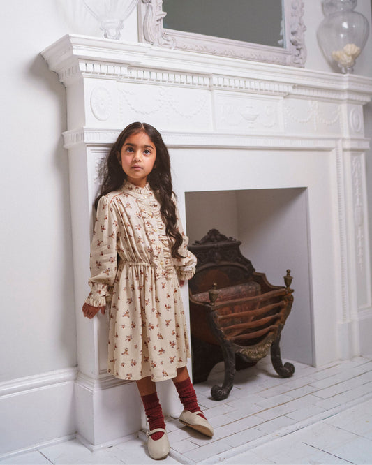 Early Sunday, Dawn Dress in Ditsy Bouquet Cream print, made from Printed Viscose Rayon Twill fabric, featuring Collar and sleeve cuffs trimmed with subtle ruffles for a nostalgic silhouette, shown in a front view of model wearing it