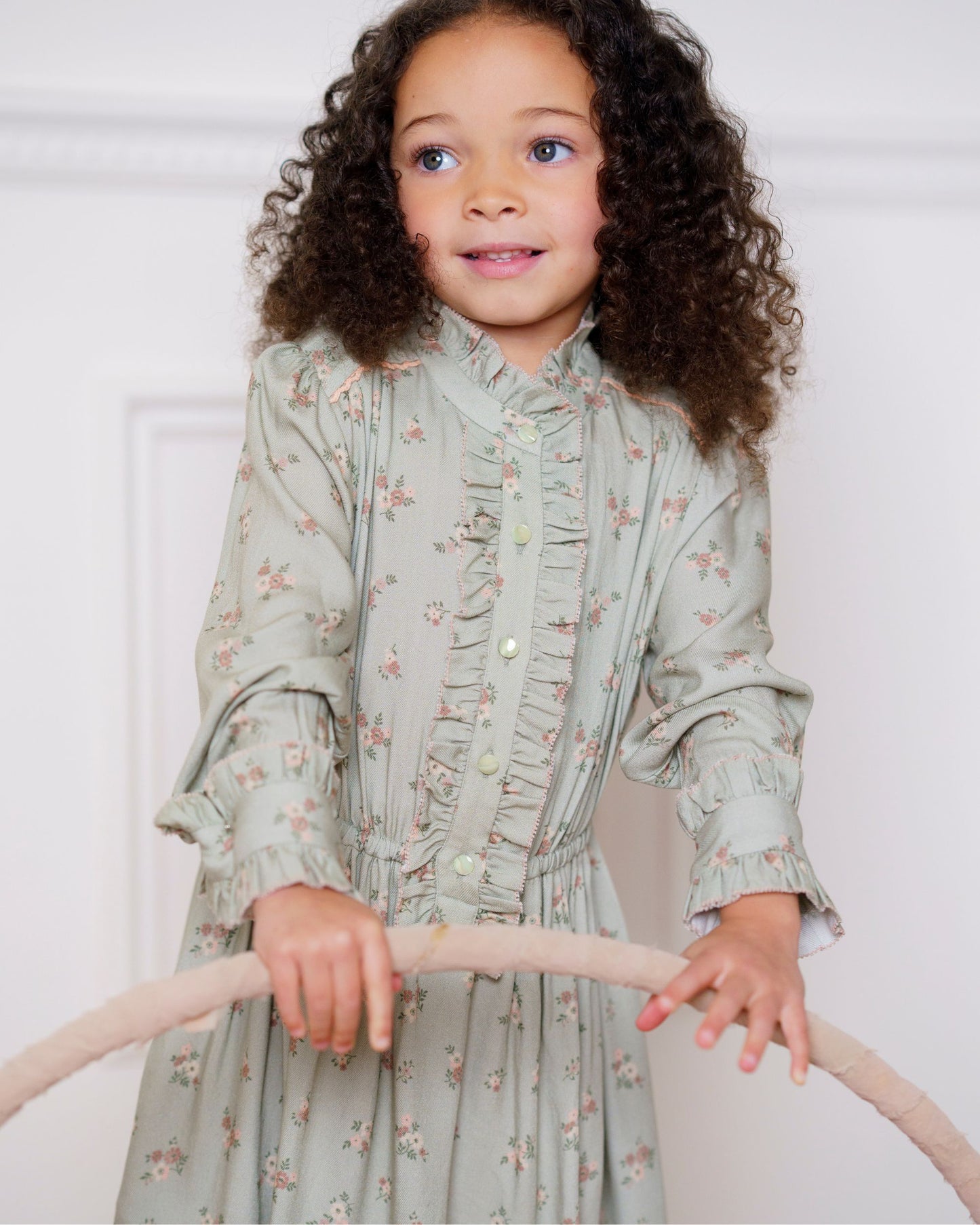 Early Sunday, Dawn Dress in Ditsy Bouquet Jade print, made from Printed Viscose Rayon Twill fabric, featuring Collar and sleeve cuffs trimmed with subtle ruffles for a nostalgic silhouette, shown in a close up shot of model wearing it