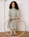 Early Sunday, Dawn Dress in Ditsy Bouquet Jade print, made from Printed Viscose Rayon Twill fabric, featuring Collar and sleeve cuffs trimmed with subtle ruffles for a nostalgic silhouette, shown in a front view of model wearing it