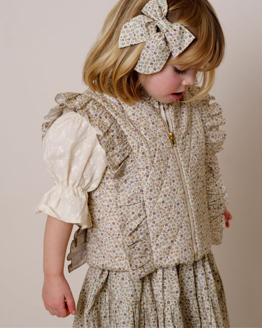 Early Sunday, Deborah Jacket in Miny Flowers print, made from Printed 30s Cotton Twill fabric, featuring Sleeveless design ideal for versatile layering in transitional weather, shown in a side view of model wearing it