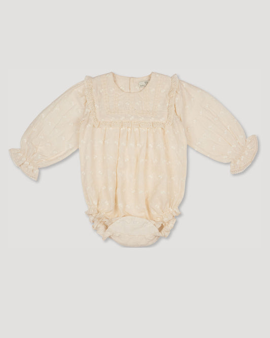 Early Sunday, Dolly Baby Bubble Romper in Hazelnut Cream color, made from All-over Embroidered Cotton Cambric fabric, featuring smocked sleeves & a square lace yoke, shown in a front flat-lay view