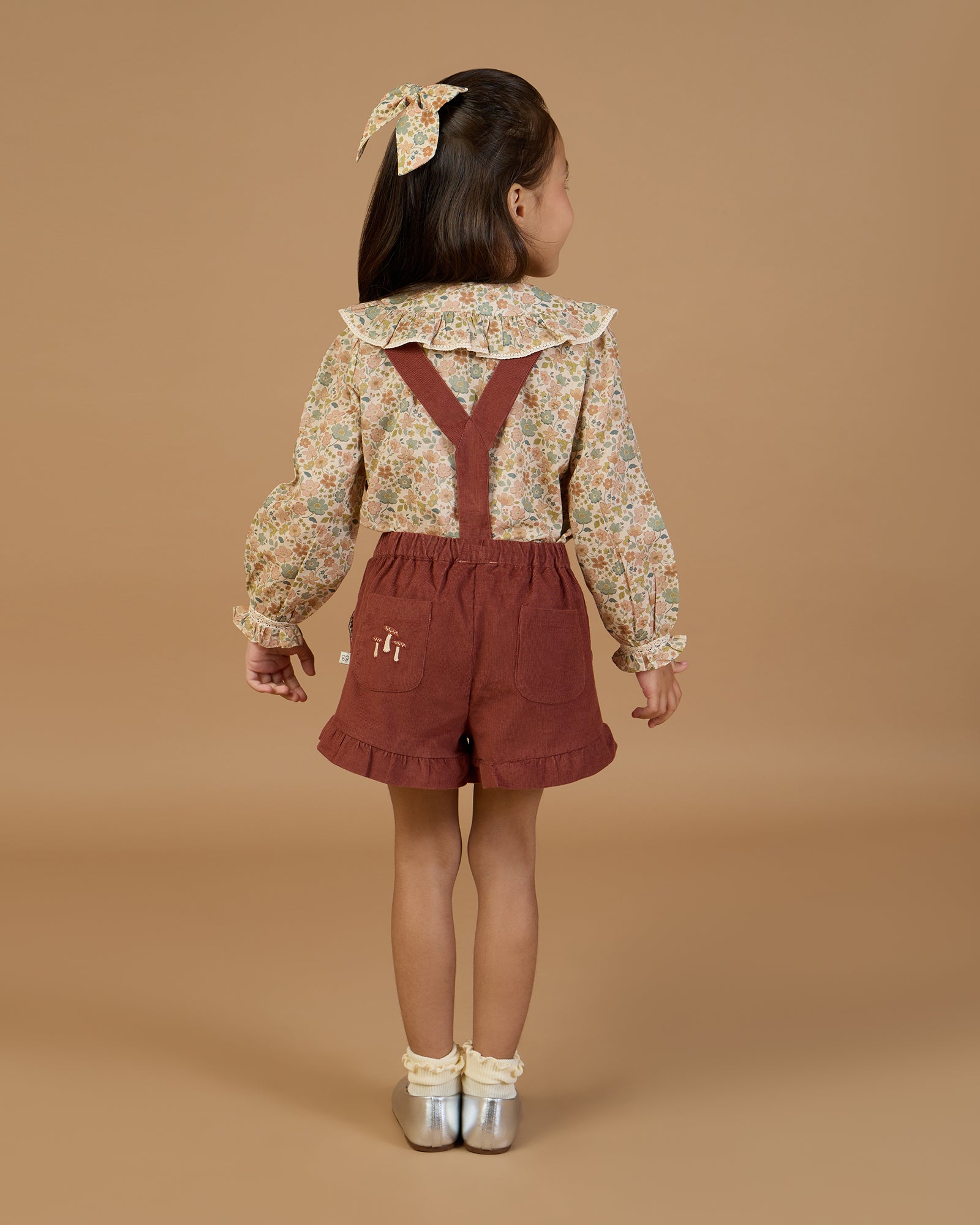 Early Sunday, Ella Blouse in Garden Flowers Cream, made from Printed Cotton Cambric fabric, featuring relaxed fit, frill detailing on the collar, and lace inserts, shown in a back view of model wearing it