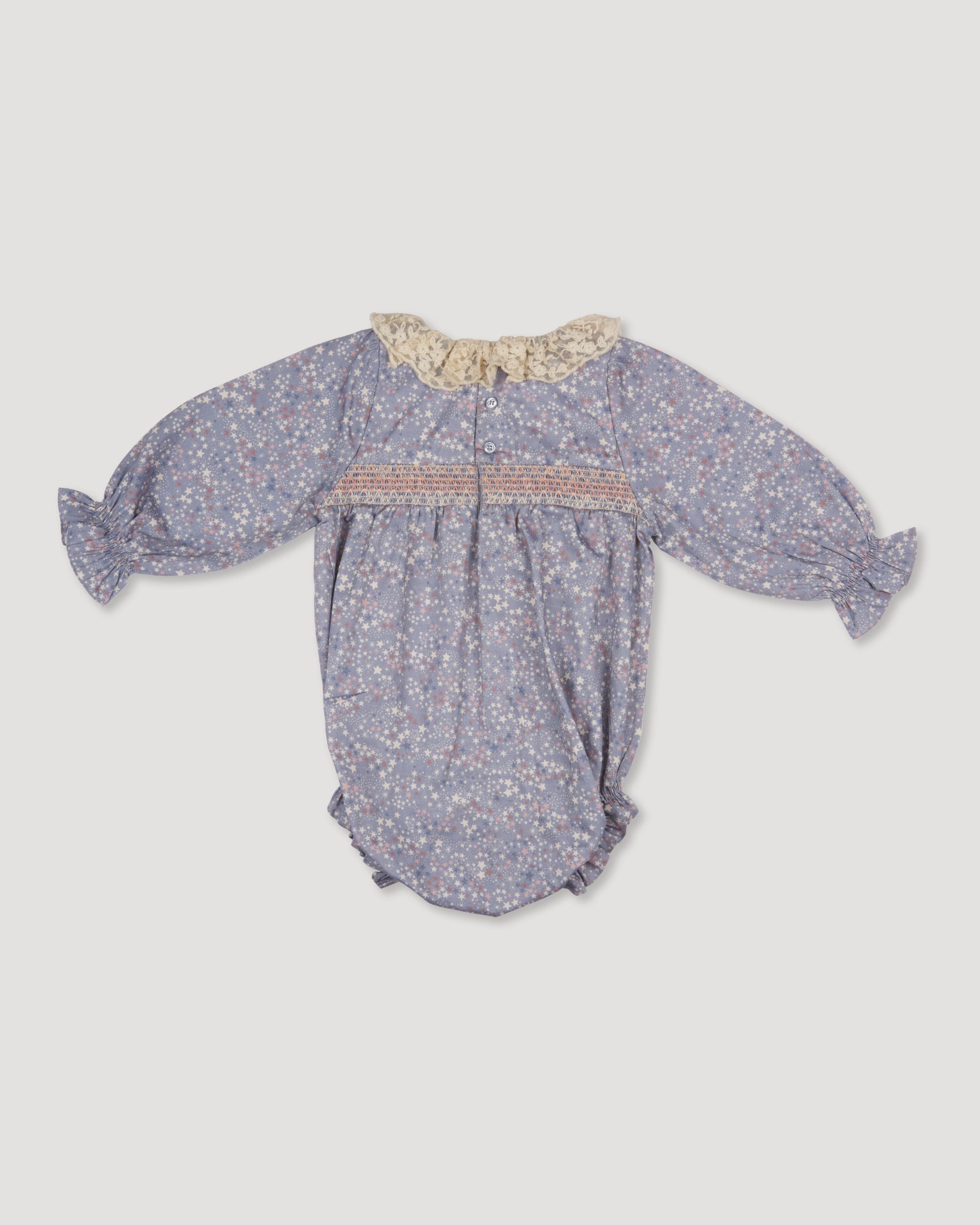 Early Sunday, Ellie Baby Bubble Romper in Celestial print, made from Printed 60s cotton satin fabric, featuring smocked sleeves with laced neckline, shown in a back flat-lay view