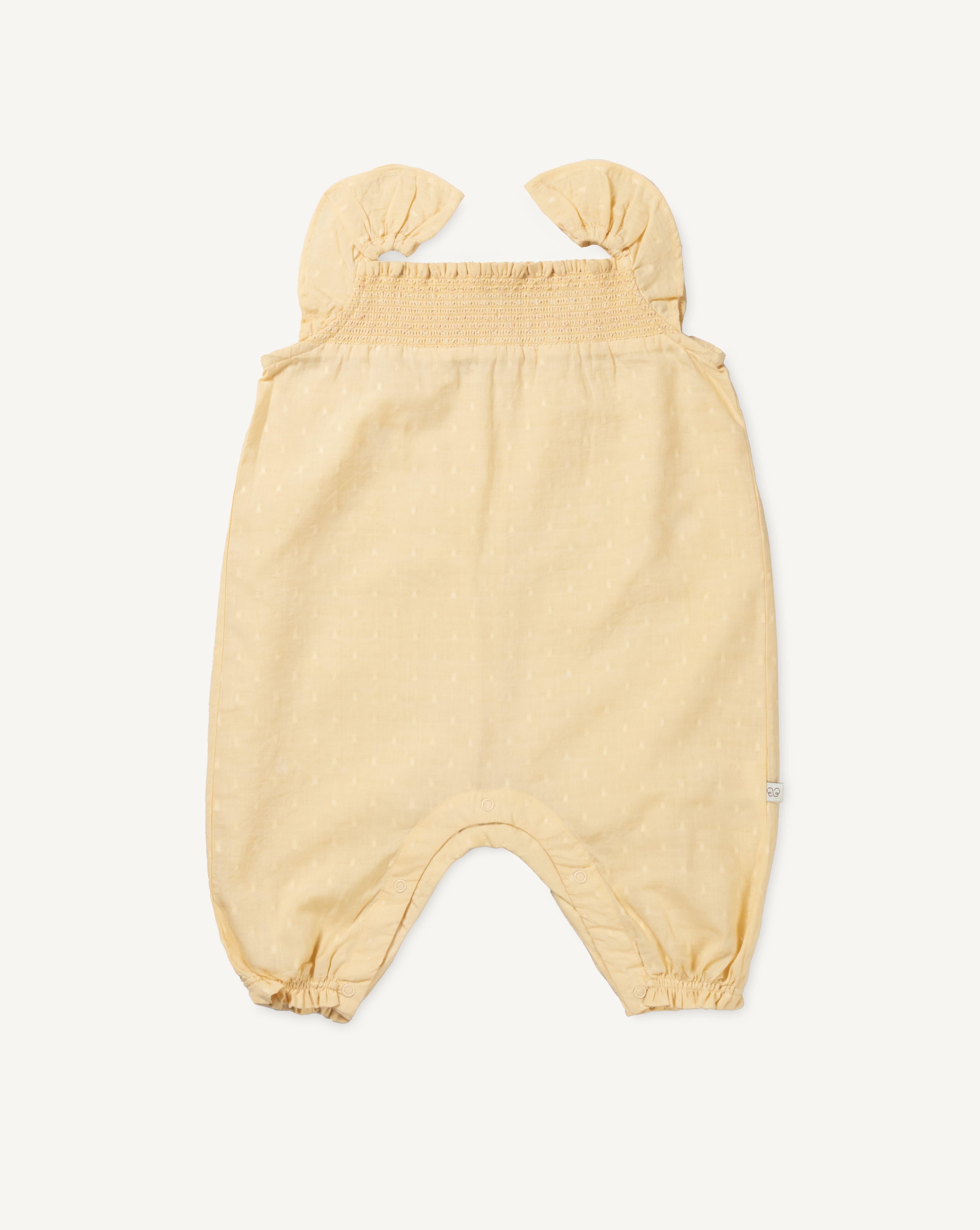 Early Sunday, Emma Baby Smocked Overalls Romper in Vanilla color, made from Cotton Dobby Swiss Dots fabric, featuring a relaxed fit with smocked chest band & frilled sleeves, shown in a back flat-lay view
