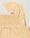 Early Sunday, Emma Baby Smocked Overalls Romper in Vanilla color, made from Cotton Dobby Swiss Dots fabric, featuring a relaxed fit with smocked chest band & frilled sleeves, shown in a closeup flat-lay view