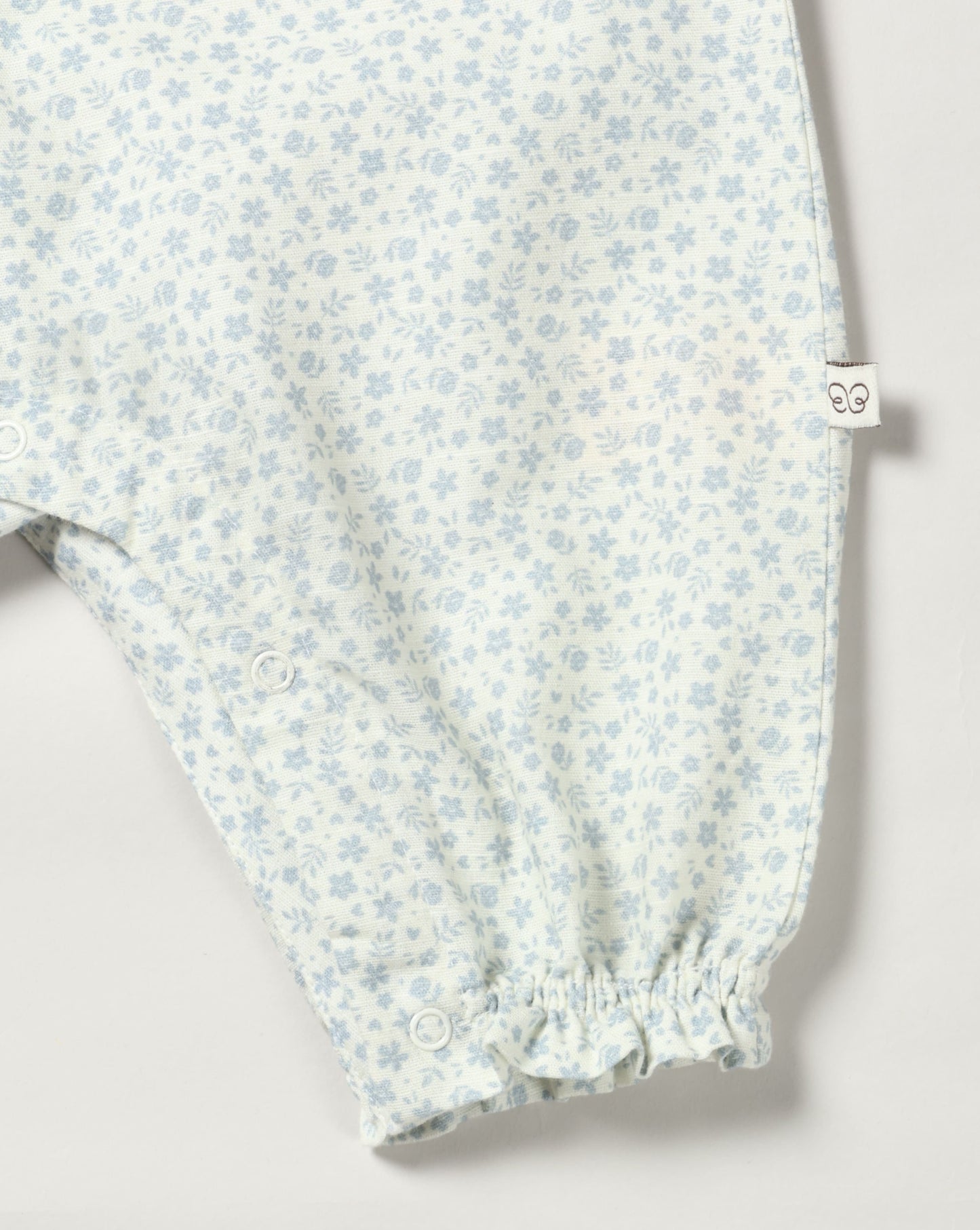 Early Sunday, Emma Baby Smocked Overalls Romper in Mini Flower print, made from Printed canvas 70% Cotton 30% Linen fabric, featuring a relaxed fit with smocked chest band & frilled sleeves, shown in a closeup flat-lay view