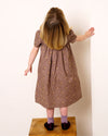Early Sunday, Erika Dress in Bark, made from All-Over Embroidered 30s Cotton Brushed Twill fabric, featuring Flowy A-line silhouette allows ease of movement and day-long comfort, shown in a back view of model wearing it