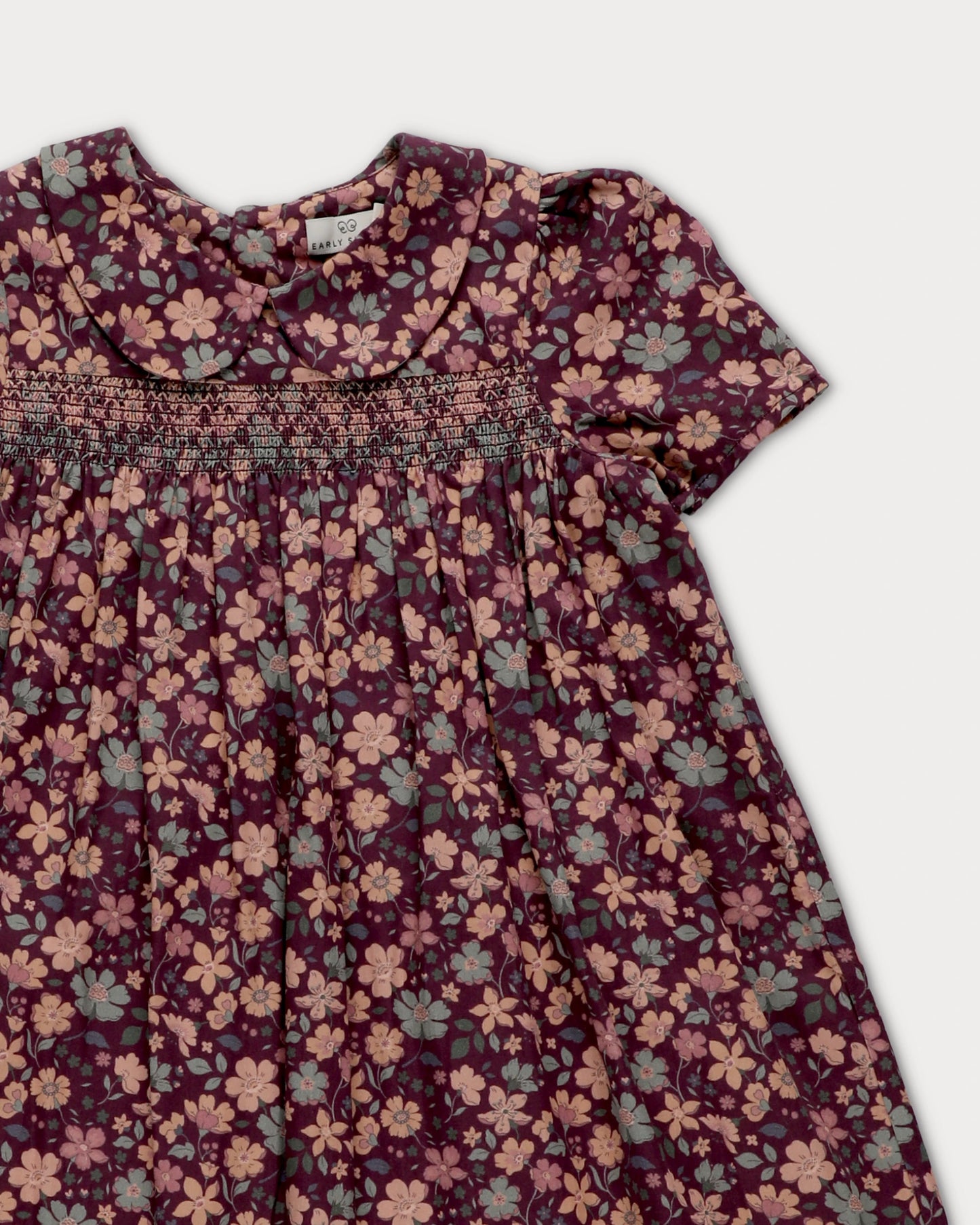 Early Sunday, Erika Dress in Plum, made from Printed Cotton Satin fabric, featuring a floral print with peter pan collar, shown in a closeup flat-lay view