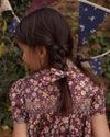 Early Sunday, Erika Dress in Plum, made from Printed Cotton Satin fabric, featuring a floral print with peter pan collar, shown in a close up shot of model wearing it