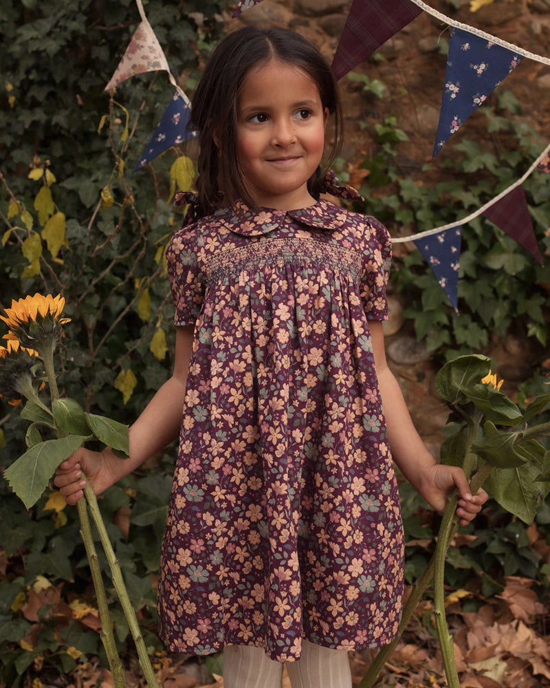 Early Sunday, Erika Dress in Plum, made from Printed Cotton Satin fabric, featuring a floral print with peter pan collar, shown in a front view of model wearing outdoors