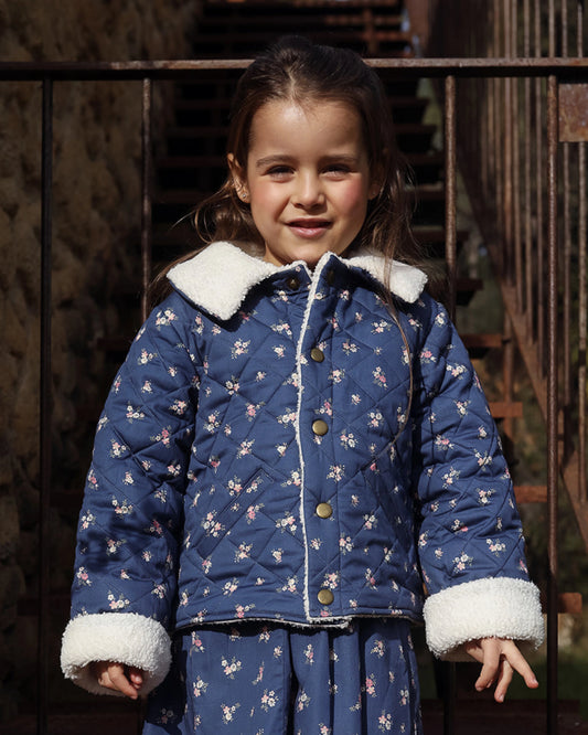 Early Sunday, Esmée Jacket in Ditsy Bouquet Navy, made from Printed Cotton Satin fabric, featuring a quilted layer with floral detailing, shown in a front view of model wearing outdoors