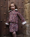 Early Sunday, Esmée Jacket in Garden Flowers Plum, made from Printed Cotton Satin fabric, featuring a quilted layer with delicate floral print and elegant detailing, shown in a front view of model wearing outdoors