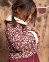 Early Sunday, Esmée Jacket in Garden Flowers Plum, made from Printed Cotton Satin fabric, featuring a quilted layer with delicate floral print and elegant detailing, shown in a side view of model wearing outdoors