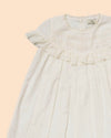 Early Sunday, Faustine Dress in Ivory color, made from 100% cotton swiss dobby tiny dots fabric, featuring Soft gathers with delicate ruffle accents, shown in a closeup flat-lay view