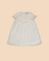 Early Sunday, Faustine Dress in Ivory color, made from 100% cotton swiss dobby tiny dots fabric, featuring Soft gathers with delicate ruffle accents, shown in a front flat-lay view