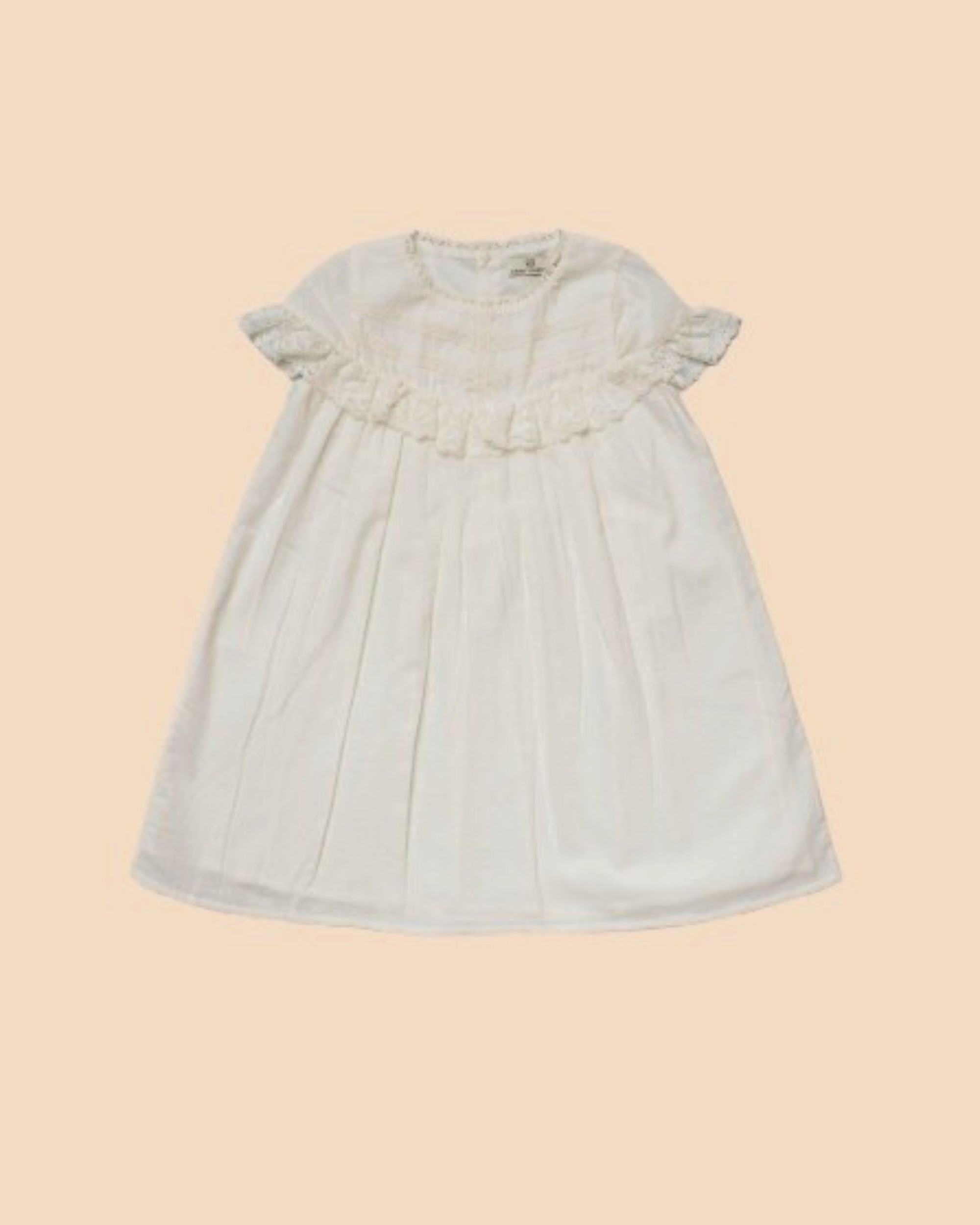Early Sunday, Faustine Dress in Ivory color, made from 100% cotton swiss dobby tiny dots fabric, featuring Soft gathers with delicate ruffle accents, shown in a front flat-lay view