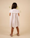 Early Sunday, Faustine Dress in Ivory color, made from 100% cotton swiss dobby tiny dots fabric, featuring Soft gathers with delicate ruffle accents, shown in a back view of model wearing it
