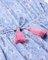 Early Sunday, Florence Dress in Tonal Floral Blue color, made from printed cotton tiny swiss dobby fabric, featuring Ruffle detailing on the yoke and sleeves, lace accents, gathered waist with tassel tie, shown in a closeup flat-lay view