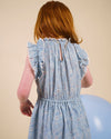 Early Sunday, Florence Dress in Tonal Floral Blue color, made from printed cotton tiny swiss dobby fabric, featuring Ruffle detailing on the yoke and sleeves, lace accents, gathered waist with tassel tie, shown in a back view of model wearing