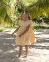 Early Sunday, Georgia Dress in Vanilla color, made from Cotton Dobby Swiss Dots fabric, featuring flutter sleeves, pintuck detailing, and a flowy, gathered silhouette, shown in a front view of model wearing it