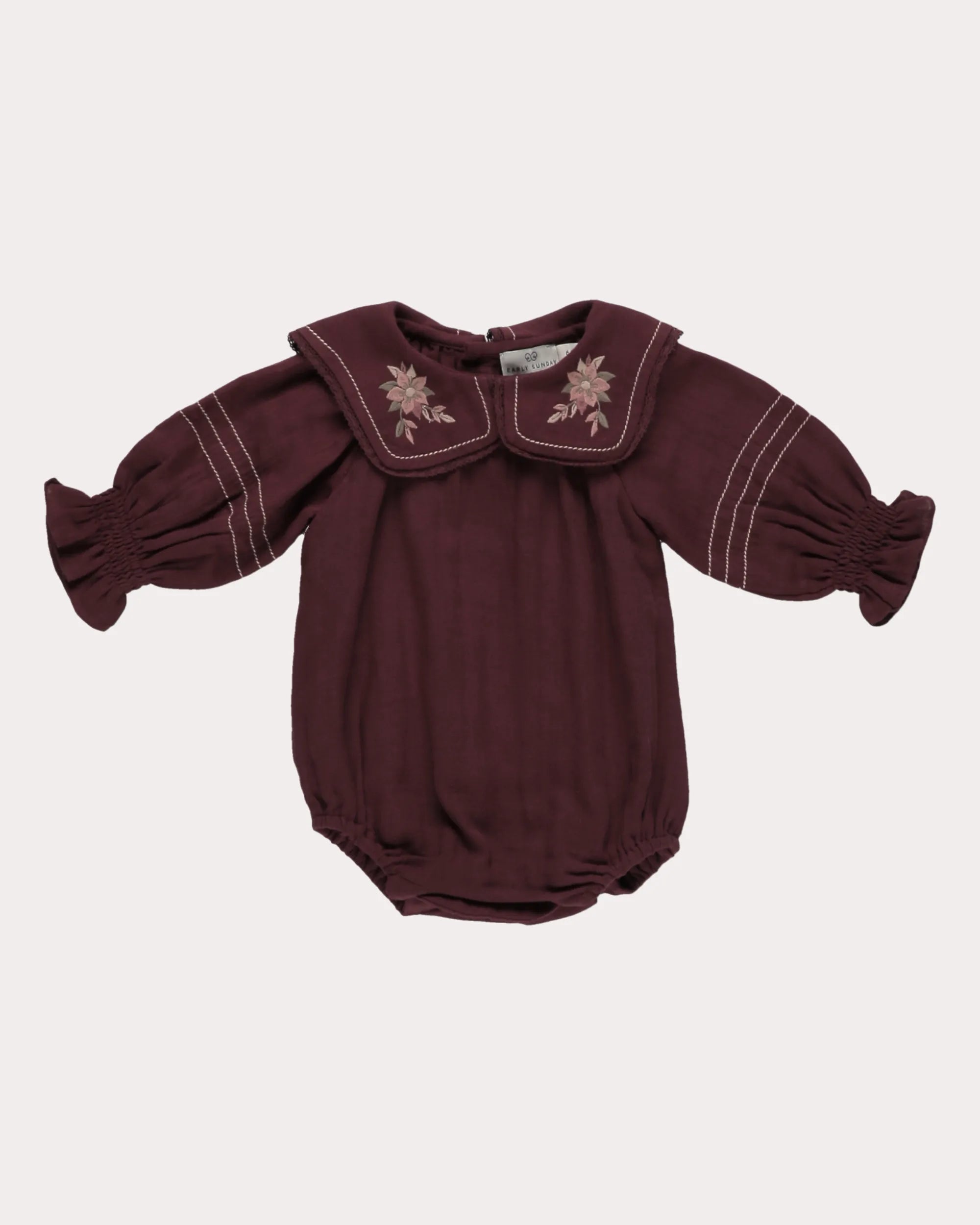 Early Sunday, Gladys Baby Bubble Romper in Plum, made from Cotton Double Gauze fabric, featuring a floral embroidered collar with beautiful lace yoke, shown in a front flat-lay view