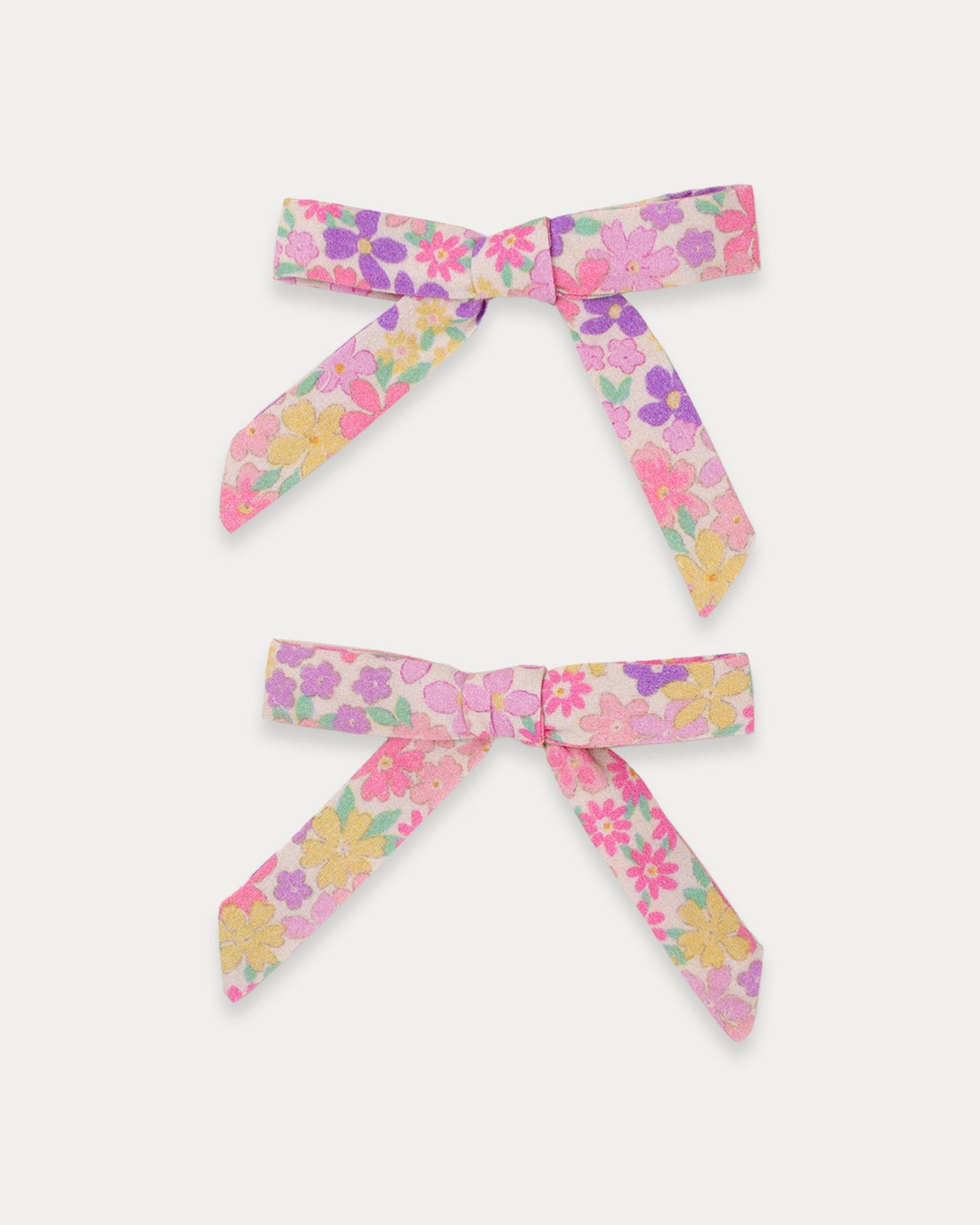 Early Sunday, Grace Clip in Emma Floral Purple color, made from Organic Printed Cotton Cambric fabric, featuring a set of two bow clips with a secure fit, shown in front flat-lay view