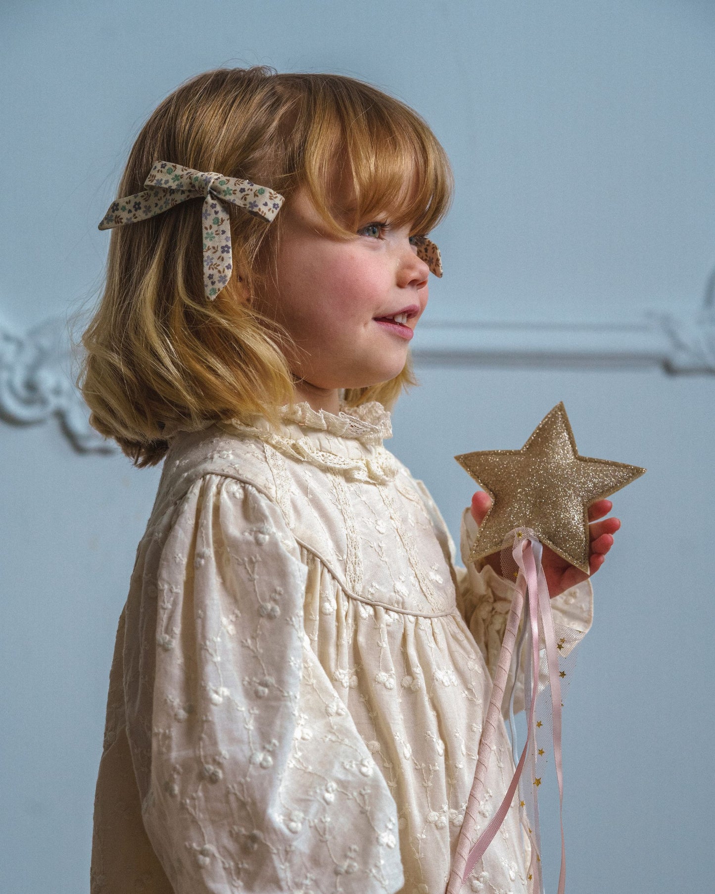 Early Sunday, Grace Clip in Mini Flowers print, made from Printed 60s Cotton Satin fabric, featuring a set of two bow clips with a secure fit, shown in a close-up side view of a model wearing it