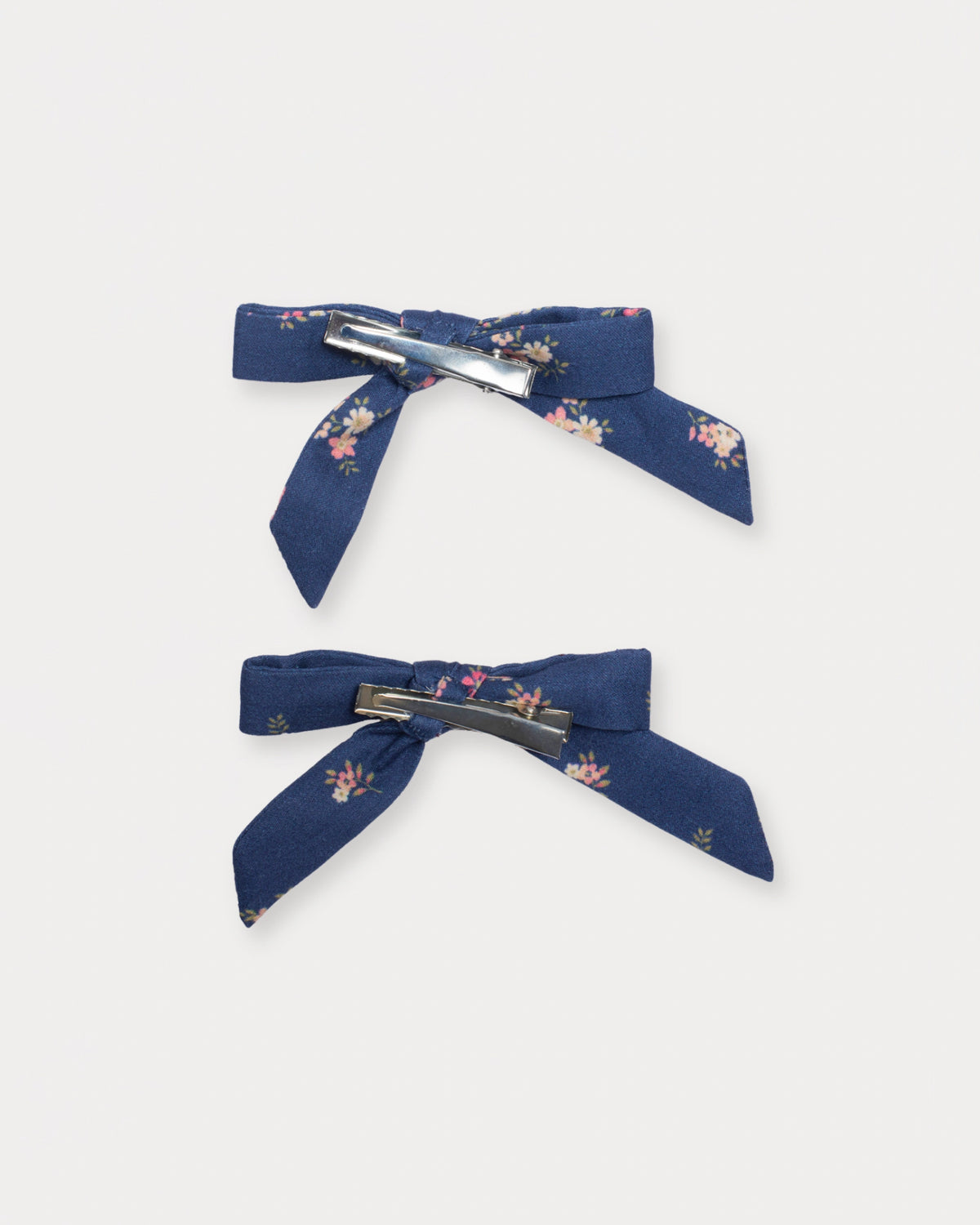 Early Sunday, Grace Clip in Ditsy Bouquet Navy Blue, made from Printed Cotton Satin fabric, featuring a set of two bow clips with a secure fit, shown in a back flat-lay view