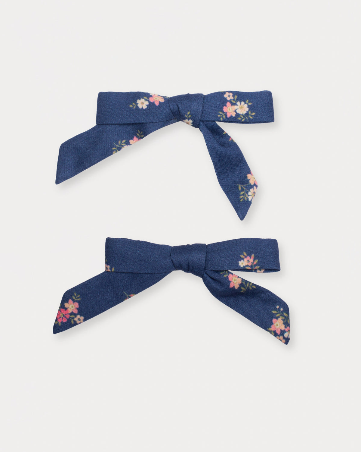 Early Sunday, Grace Clip in Ditsy Bouquet Navy Blue, made from Printed Cotton Satin fabric, featuring a set of two bow clips with a secure fit, shown in a front flat-lay view