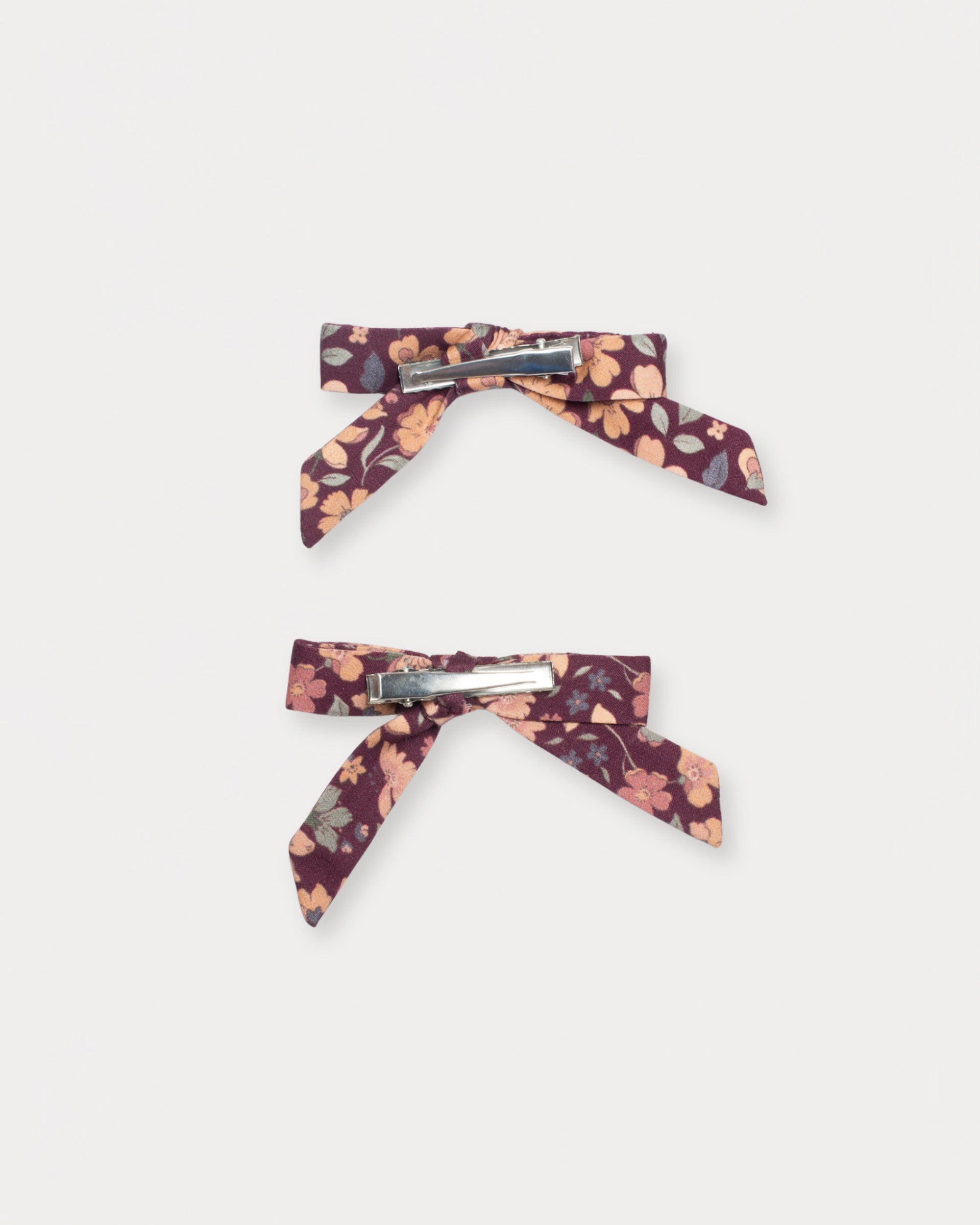 Early Sunday, Grace Clip in Garden Flowers Plum, made from Printed Cotton Satin fabric, featuring a set of two bow clips with a secure fit, shown in a back flat-lay view