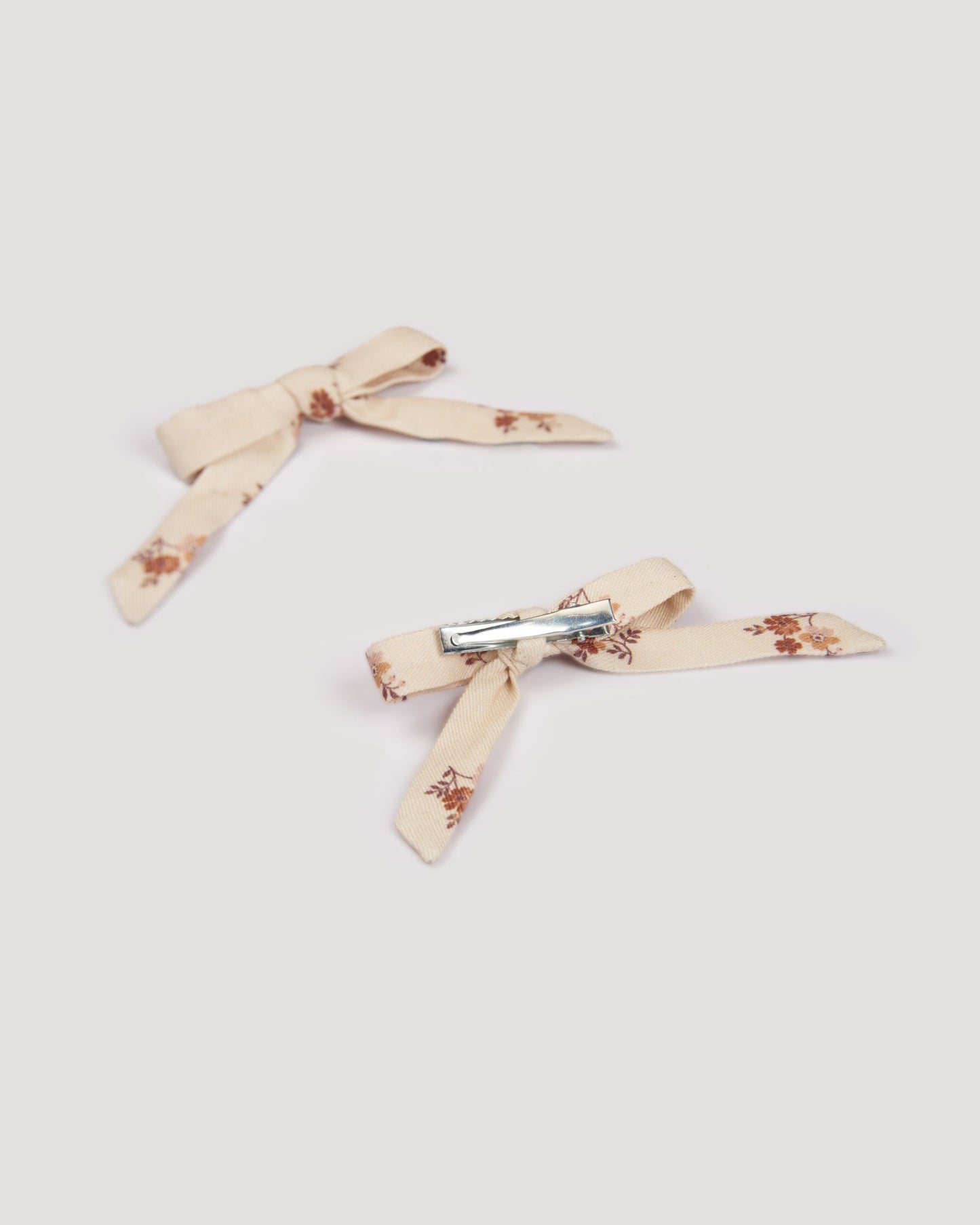 Early Sunday, Grace Clip in Ditsy Bouquet Cream print, made from Printed Viscose Twill fabric, featuring a set of two bow clips with a secure fit, shown in a back flat-lay view