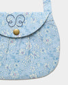 Early Sunday, Hudson Purse in Tonal Floral Blue color, made from Printed Cotton Tiny Swiss Dobby fabric, featuring a gathered sling purse design with a flap closure, shown in closeup flat-lay view
