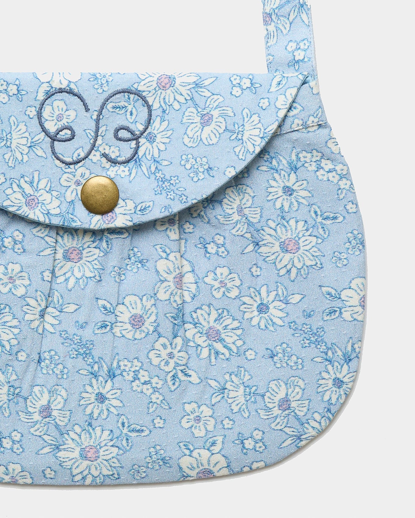 Early Sunday, Hudson Purse in Tonal Floral Blue color, made from Printed Cotton Tiny Swiss Dobby fabric, featuring a gathered sling purse design with a flap closure, shown in closeup flat-lay view