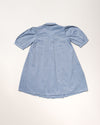 Early Sunday, Jane Dress in Summer Sky color, made from 100% cotton chambray fabric, featuring Smocked / embroidered yoke, peter pan collar and puffed short sleeves, shown in a back flat-lay view