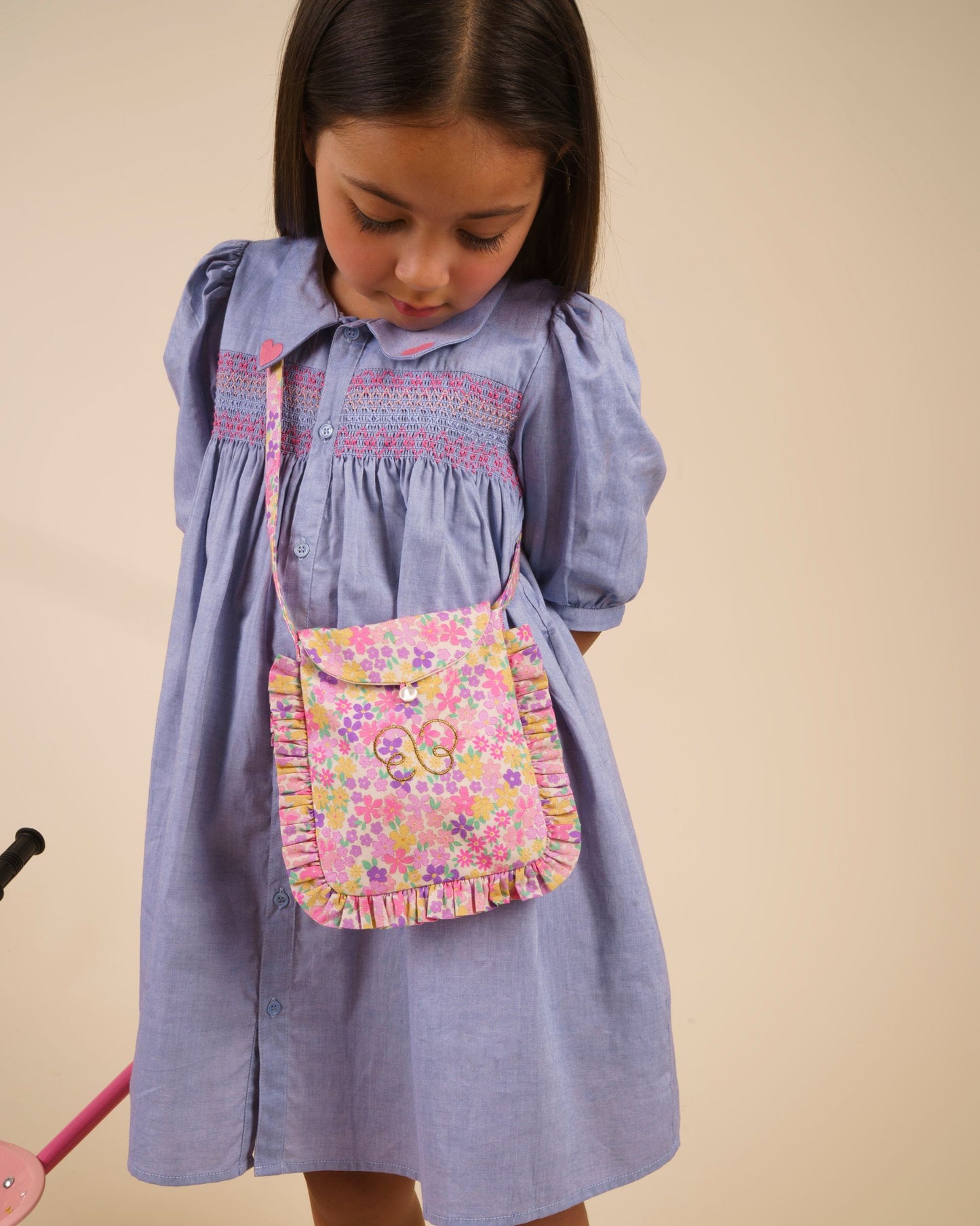 Early Sunday, Jane Dress in Summer Sky color, made from 100% cotton chambray fabric, featuring Smocked / embroidered yoke, peter pan collar and puffed short sleeves, shown in a Model side pose / slight angle