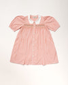 Early Sunday, Jane Dress in Peony color, made from 100% cotton gingham checks fabric, featuring Smocked / embroidered yoke, peter pan collar and puffed short sleeves, shown in a front flat-lay view