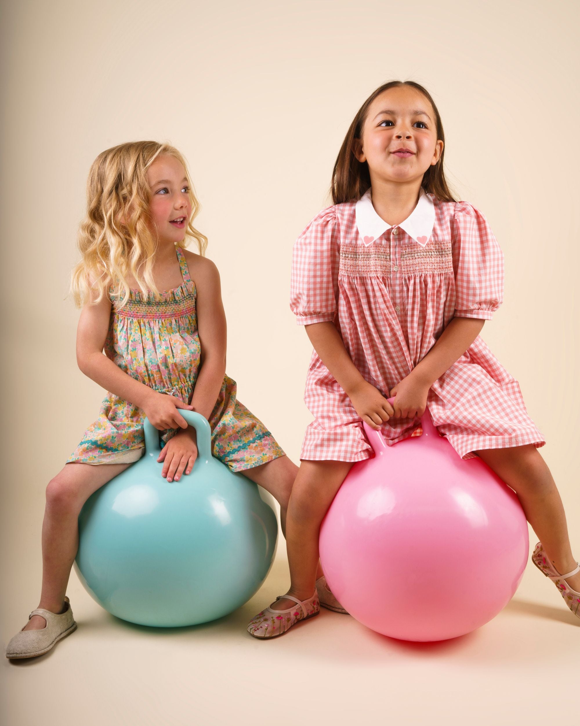 Early Sunday, Jane Dress in Peony color, made from 100% cotton gingham checks fabric, featuring Smocked / embroidered yoke, peter pan collar and puffed short sleeves, shown in a model in motion