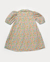 Early Sunday, Jane Dress in Emma Floral Mint color, made from printed 60s cotton cambric fabric, featuring Smocked / embroidered yoke, peter pan collar and puffed short sleeves, shown in a back flat-lay view