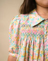 Early Sunday, Jane Dress in Emma Floral Mint color, made from printed 60s cotton cambric fabric, featuring Smocked / embroidered yoke, peter pan collar and puffed short sleeves, shown in a close up shot of model wearing it