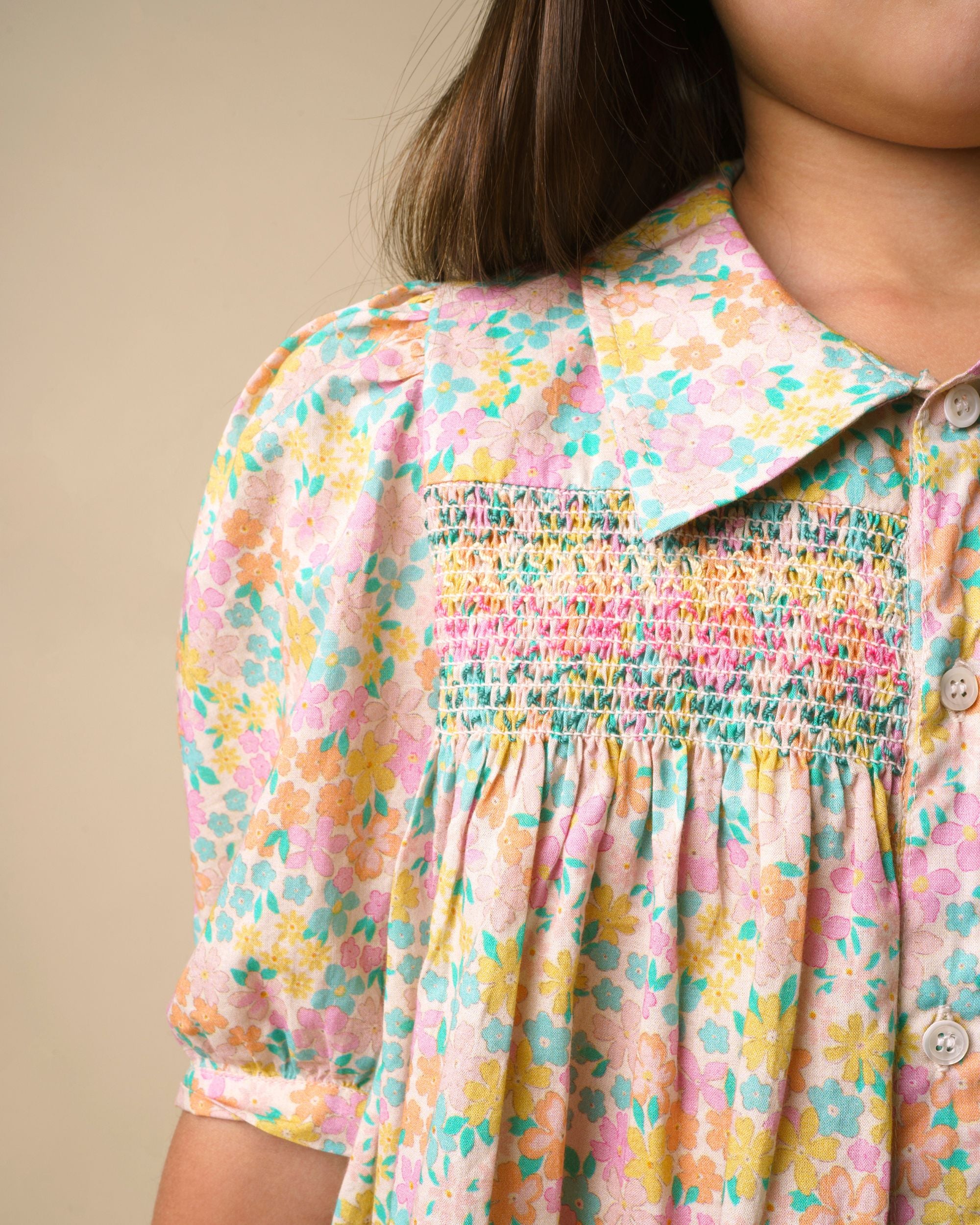 Early Sunday, Jane Dress in Emma Floral Mint color, made from printed 60s cotton cambric fabric, featuring Smocked / embroidered yoke, peter pan collar and puffed short sleeves, shown in a close up shot of model wearing it