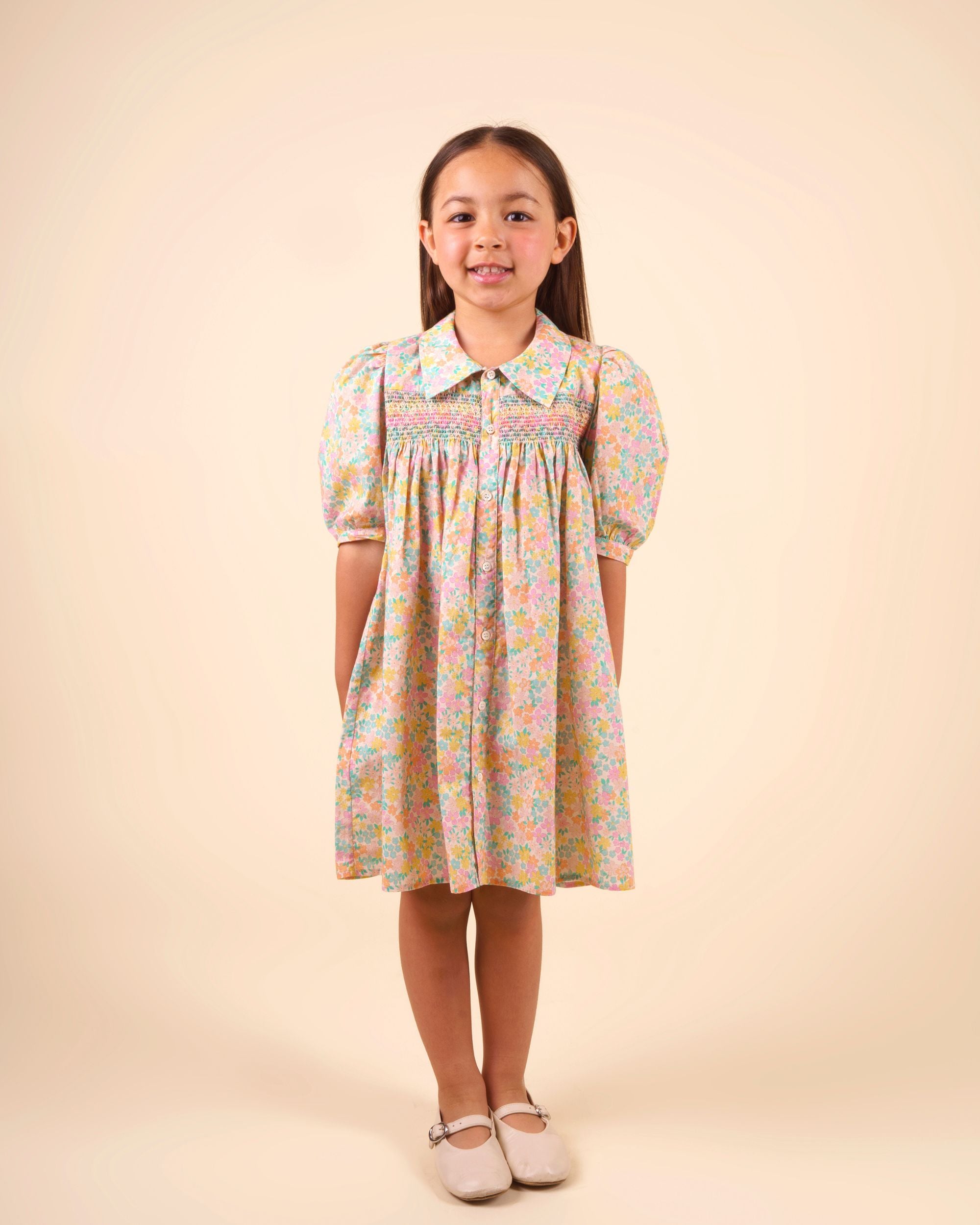 Early Sunday, Jane Dress in Emma Floral Mint color, made from printed 60s cotton cambric fabric, featuring Smocked / embroidered yoke, peter pan collar and puffed short sleeves, shown in a front view of model wearing