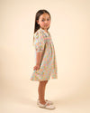 Early Sunday, Jane Dress in Emma Floral Mint color, made from printed 60s cotton cambric fabric, featuring Smocked / embroidered yoke, peter pan collar and puffed short sleeves, shown in a side view of model wearing
