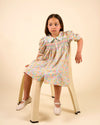 Early Sunday, Jane Dress in Emma Floral Mint color, made from printed 60s cotton cambric fabric, featuring Smocked / embroidered yoke, peter pan collar and puffed short sleeves, shown in a Model side pose / slight angle