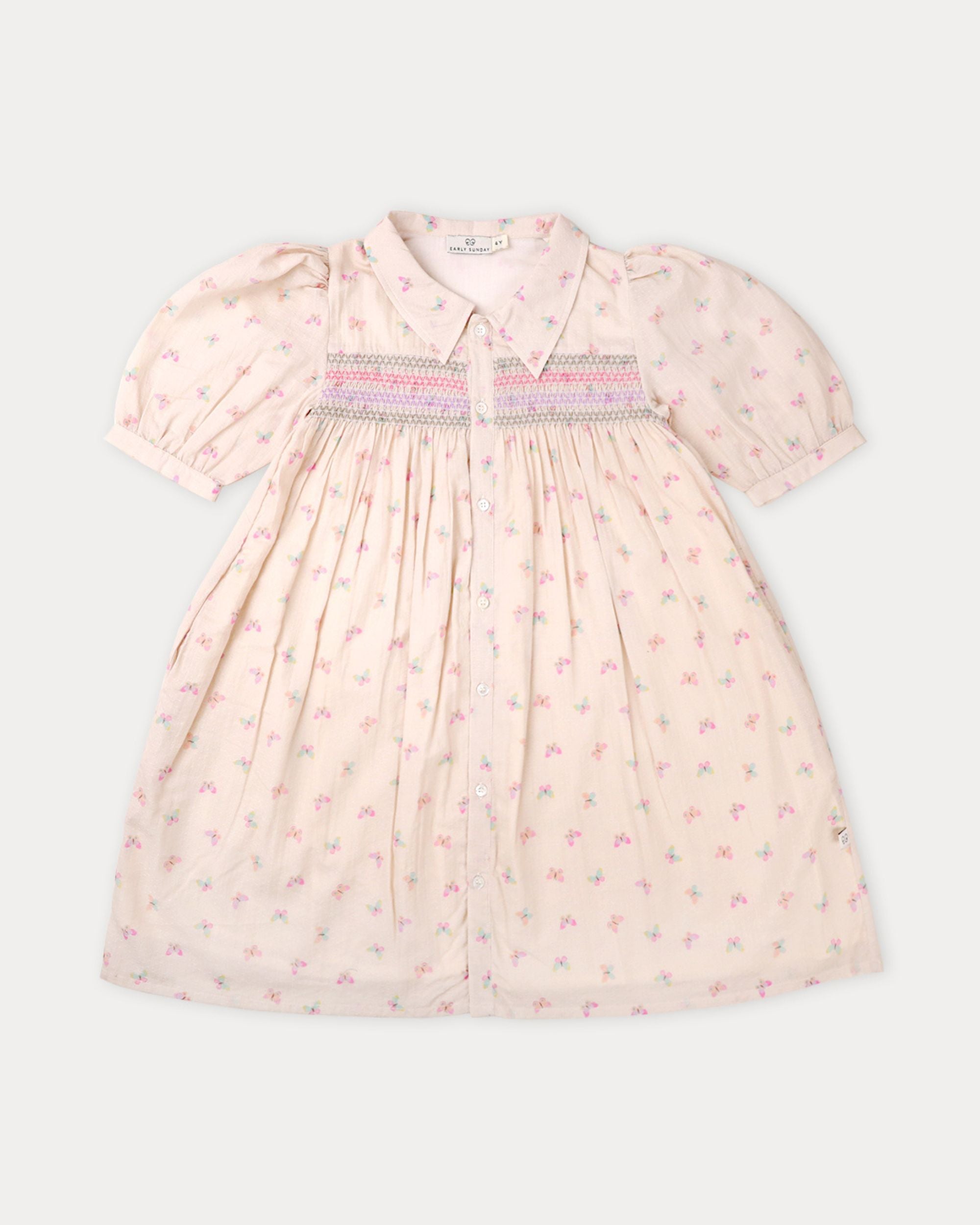 Early Sunday, Jane Dress in Butterfly Print color, made from printed cotton tiny swiss dobby fabric, featuring Smocked / embroidered yoke, peter pan collar and puffed short sleeves, shown in a front flat-lay view