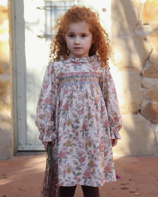 Early Sunday, Jeanette Dress in Bloom, made from Printed Viscose Twill fabric, featuring smocked chest with frilled neckline and soft gathered puff sleeves, shown in a front view of model wearing outdoors